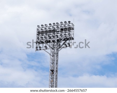 Stadium floodlight tower under cloudy sky
