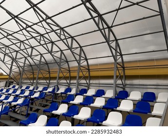 the stadium has a tribune with an elevated auditorium covered with Plexiglas. the roof is transparent and in the shape of an arch or a wave. plastic seats for outdoor matches,  - Shutterstock ID 2285932483