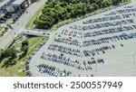 Stadium parking lot in Arlington, Texas, busy electric, gas vehicles entering large outdoor space with parallel pattern and pavement marking, parking management in metropolitan urban area, aerial. USA