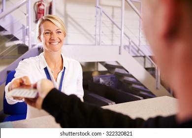 Staff At Airport Check In Desk Handing Ticket To Passenger