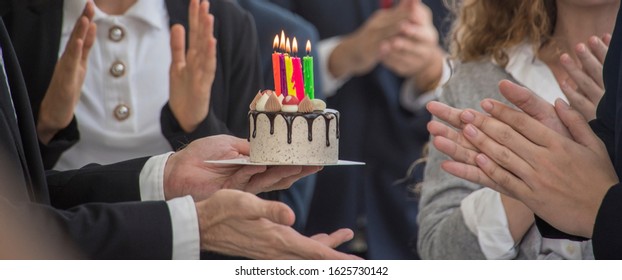 Staff friends surprise singing happy and clapping to celebrate birthdays with birthday cake and there were candles on the cake party in meeting 