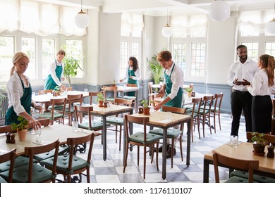 Staff Laying Tables In Empty Restaurant