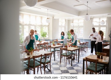 Staff Laying Tables In Empty Restaurant