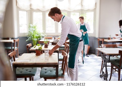 Staff Laying Tables In Empty Restaurant