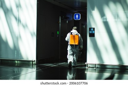 A Staff Man Wearing White Protective Suit In Airport Cleaning Disinfectant Fumigation, Disinfecting Cleaning Coronavirus Protection. Disinfection, Covid 19 Safety Control Sterilization. Safe Travel.