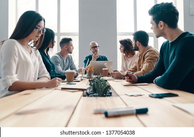 Staff Meeting. Group Of Young Modern People In Smart Casual Wear Discussing Something While Working In The Creative Office          