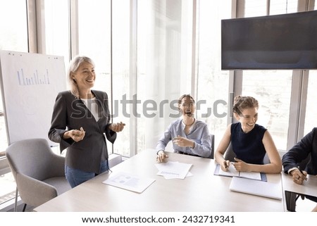 Staff members take part in educational seminar sit at desk in modern boardroom, listen to middle-aged businesswoman, laughing, joking, having pleasant talk. Business meeting event, teambuilding, fun 商業照片 © 