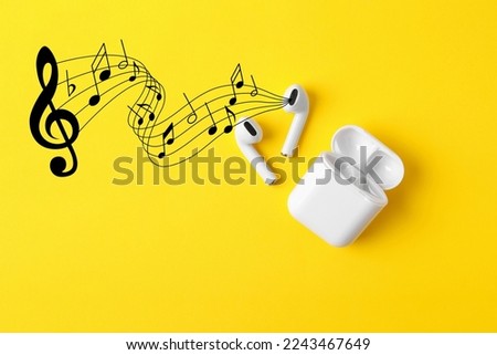 Staff with music notes and treble clef flowing from white wireless earphones on yellow background, top view