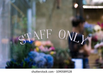 Staff Only Sign On Window With Blurry Background Of Florist Working In Floral Shop