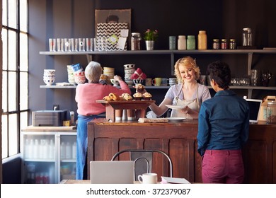 Staff Serving Customer In Busy Coffee Shop