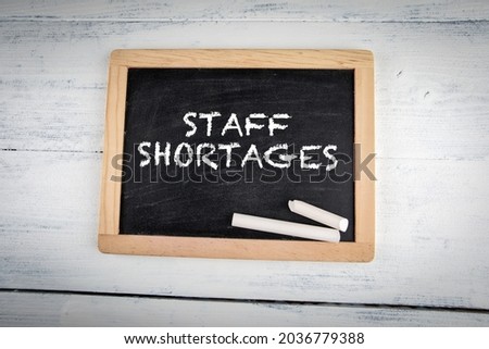 Staff Shortages. Chalk board with white pieces of chalk on a wooden table.