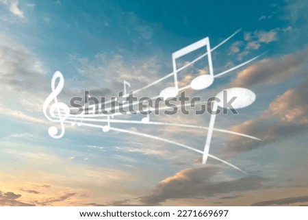 Staff with treble clef and musical notes against sunset sky