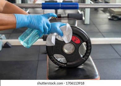 Staff using wet wipe and disinfectant from the bottle spraying weight plate in gym. Antiseptic,disinfection ,cleanliness and healthcare. Anti bacterial and Corona virus COVID19. - Powered by Shutterstock