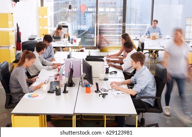 Staff walking through a busy open plan office, side view - Shutterstock ID 629123981