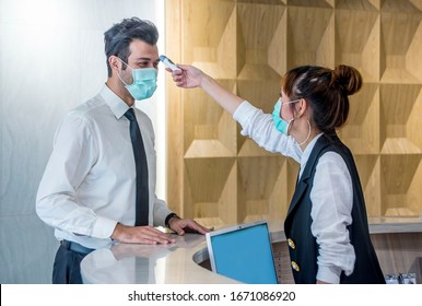 Staff woman wear protective masks at the counter used the digital thermometer to measure the temperature of visitors at the building.Measures to prevent people with fever, Covid 19 concept - Shutterstock ID 1671086920