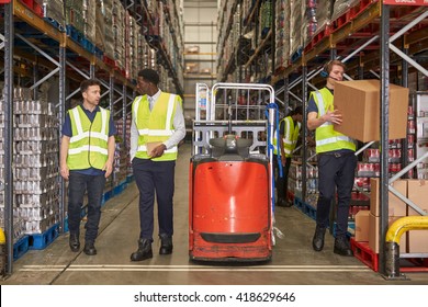 Staff At Work In The Aisle Of A Busy Distribution Warehouse