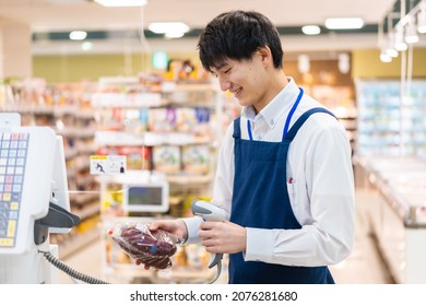 Staff working at the cash register in a supermarket - Shutterstock ID 2076281680