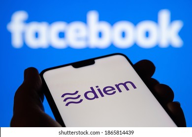 Stafford, United Kingdom - December 1 2020: Facebook Diem currency logo on the smartphone silhouette hold in a hand and blurred Facebook logo on the background. 