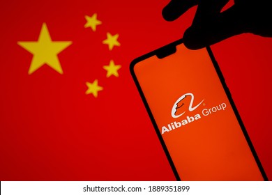 Stafford, United Kingdom - January 3 2021: Alibaba logo on a silhouette of smartphone which is hold on the edge. Concept for government probe and investigation of Alibaba group. Not a montage.