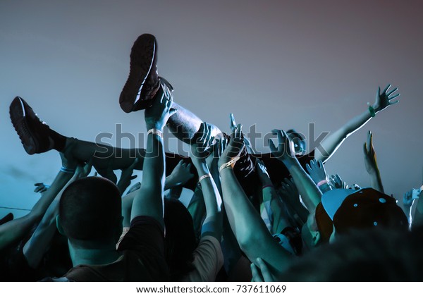 Stage\
diving. Crowd surfing during a musical\
performance