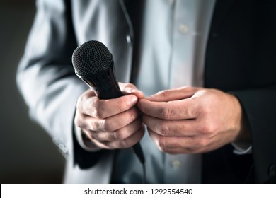 Stage Fright Concept. Nervous And Shy Public Speaker With Microphone. Business Man Afraid Of Giving Speech For Crowd Of People Or Audience. Sweaty Hands Holding Mic. Bad Presentation. Stressed Singer.