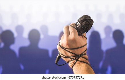 Stage Fright In Public Speaking Or Bad Karaoke Singing Live In Front Of Crowd Of People. Problem With Speech Or Failed Talent Show Performance. Microphone Wire, Cable And Cord Wrapped Around Hand. 