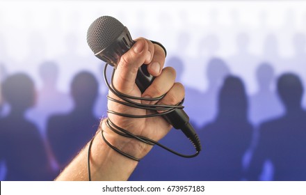 Stage Fright In Public Speaking Or Bad Karaoke Singing Live In Front Of Crowd Of People. Problem With Speech Or Failed Talent Show Performance. Microphone Wire, Cable And Cord Wrapped Around Hand. 