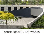 Stage with large screen is located in front of wide semicircular benches for spectators. Mature oak trees grow on terraces of amphitheater. City park "Krasnodar" or "Galitsky Park". Sunny spring 2024