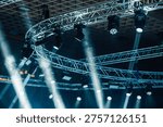 Stage lighting setup showcasing multiple spotlights and moving heads attached to a metal truss system, beams cutting through atmospheric haze