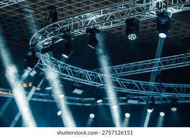 Stage lighting setup showcasing multiple spotlights and moving heads attached to a metal truss system, beams cutting through atmospheric haze