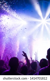 Stage lights and crowd of audience with hands raised at a music festival. Fans enjoying the party vibes. - Shutterstock ID 1414701812