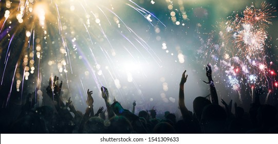 Stage Lights And Crowd Of Audience With Hands Raised At A Music Festival. Fans Enjoying The Party Vibes. New Years Eve Concept. 