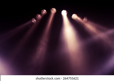 Stage lights. Several projectors in the dark. Purple spotlight strike through the darkness - Shutterstock ID 264755621