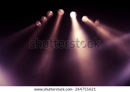 Stage lights. Several projectors in the dark. Purple spotlight strike through the darkness