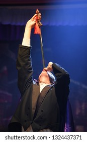 A Stage Magician Takes The Centre Spotlight During His Sword Swallowing Act