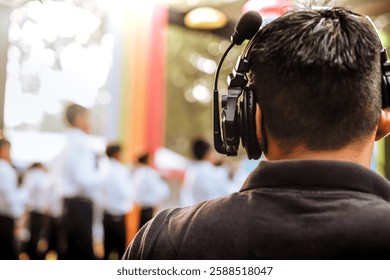 Stage manager using wireless intercom headset while watching and directing stage live performance