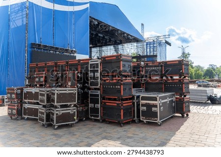 Stage setup with scaffolding and flight cases ready for a concert event, showing technical gear and logistics.