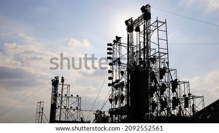 Stage structure silhouette. Concert stage with outdoor lighting and sound equipment on cloudy sky background and afternoon sun with copy space. selective focus