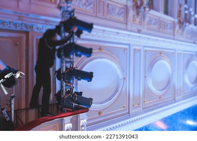 Stage worker assistant sets up lights, light engineer, lighting technician adjusting lights for concert music show in hall, installation of professional equipment with projectors and led lights - Powered by Shutterstock