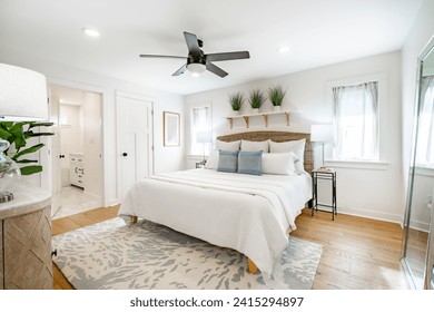 Staged bedroom interior with wooden floors, bright spacious rooms with decor clean crisp linens bedding throw pillows hardwood floors and ocean view