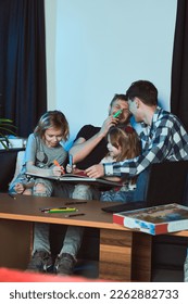    Staged photo  Homosexual couple   their children  two cute girls  at home    They are all sitting together   drawing and markers in notebook                              