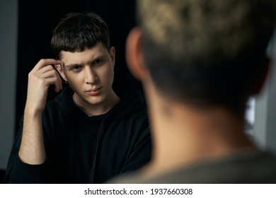    Staged Photo Illustrates Problems And Conflicts In Gay Couple Relationships. Moment Of Showdown: Young Black-haired Man With Furrowed Brow Is Standing In Front Of His Partner And Listening To Him. 