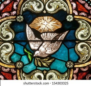 Stained glass window depicting peace, a dove with olive branch in its beak