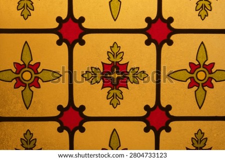 Stained glass window featuring repeating floral motifs and geometric shapes