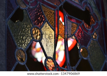 Stained glass/leaded light: damaged leadlight of a French mausoleum backlit by evening sun.