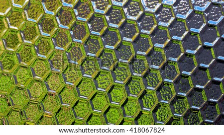 Stained textured semitransparent glass background. Bright reflections and deep shadows on honeycomb pattern