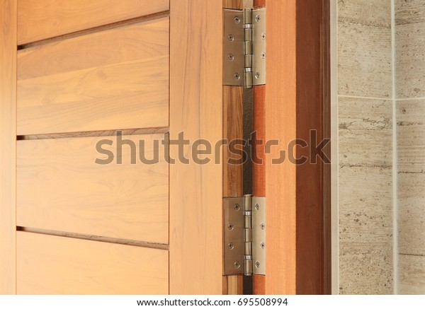 Stainless door hinges on\
wooden swing door