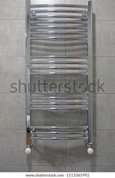 Stainless electric towel dryer for the bathroom.\
Drying is mounted on a wall with gray tiles, divided into many\
sections. Towel dryer for drying towels in the bathroom, heating\
and drying the\
bathroom