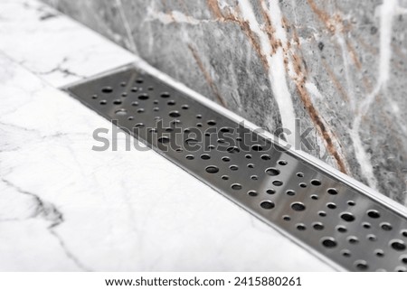 Stainless linear shower drain system in shower room.