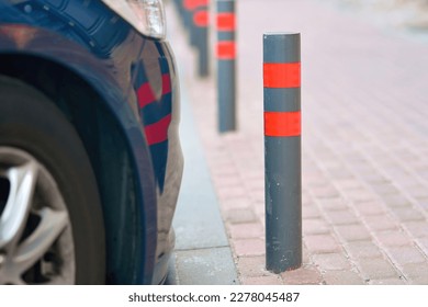 Stainless parking poles separating sidewalk from parking lot. Steel bollards on footpath near parking lot. 